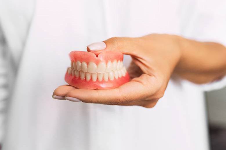 Dentist holding full dentures in Edmonton