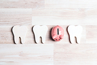 A pink piggy bank with tooth illustrations on a light wooden background